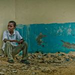 Child sitting with his back to a wall - Dental Mission in the Dominican Republic
